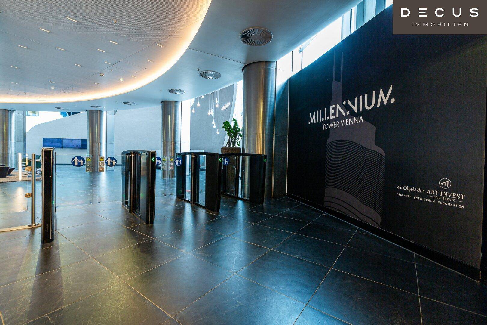 Moderne und geräumige Lobby mit dunklem Fliesenboden, eleganten Säulen und Zugangskontrolle.