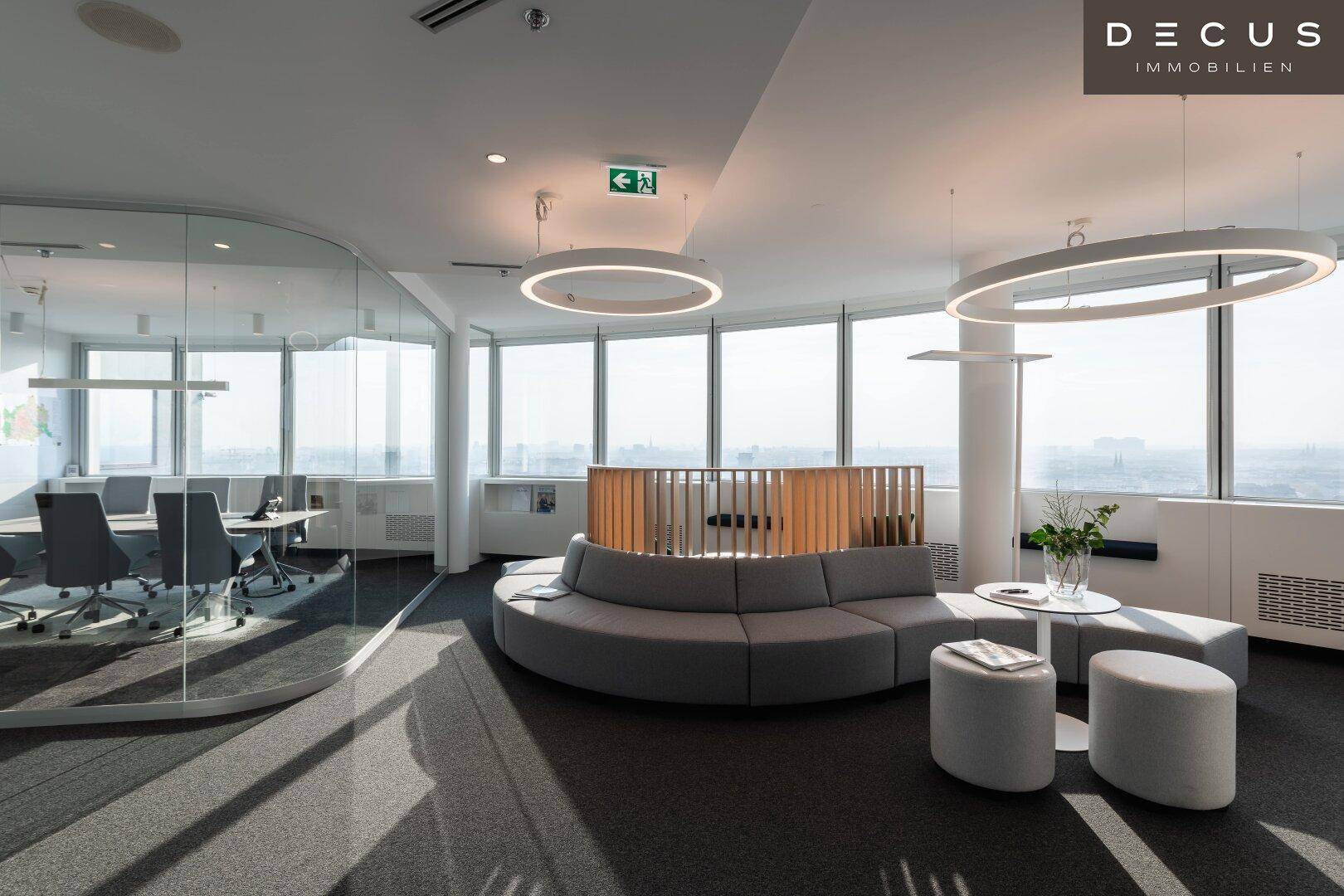 Helle, offene Bürofläche mit Lounge-Bereich, Besprechungsraum und großen Fenstern mit Stadtblick.