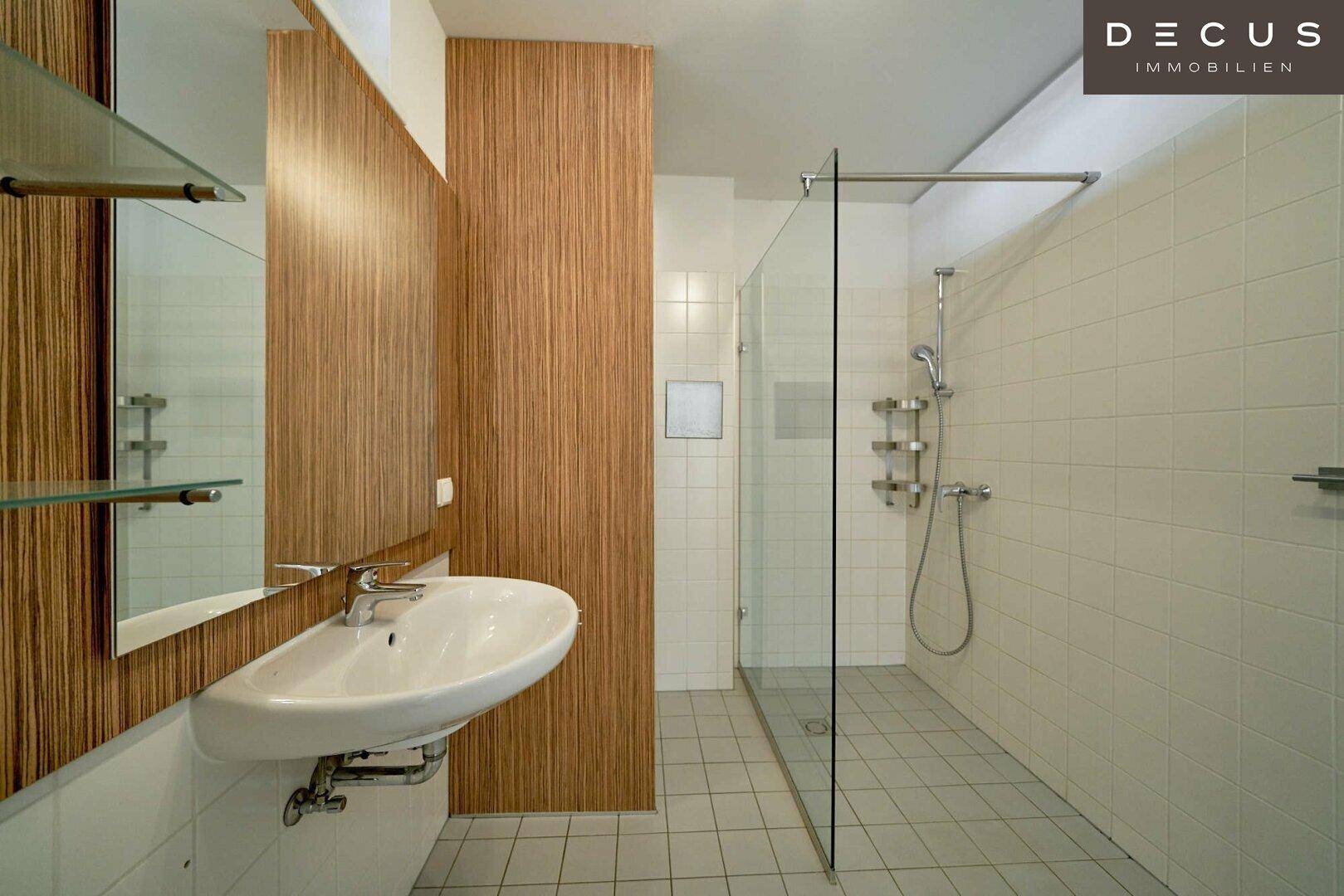 Modernes Badezimmer mit begehbarer Dusche, Wandwaschbecken und hellen Fliesen.