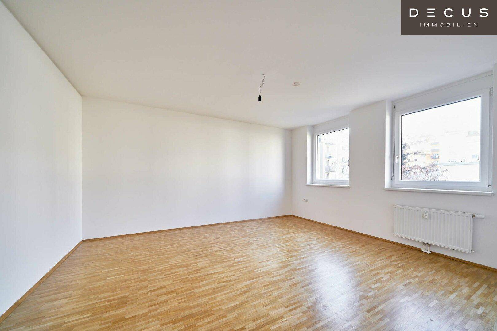 Geräumiges, helles Zimmer mit Parkettboden und zwei Fenstern, bietet viel Tageslicht.