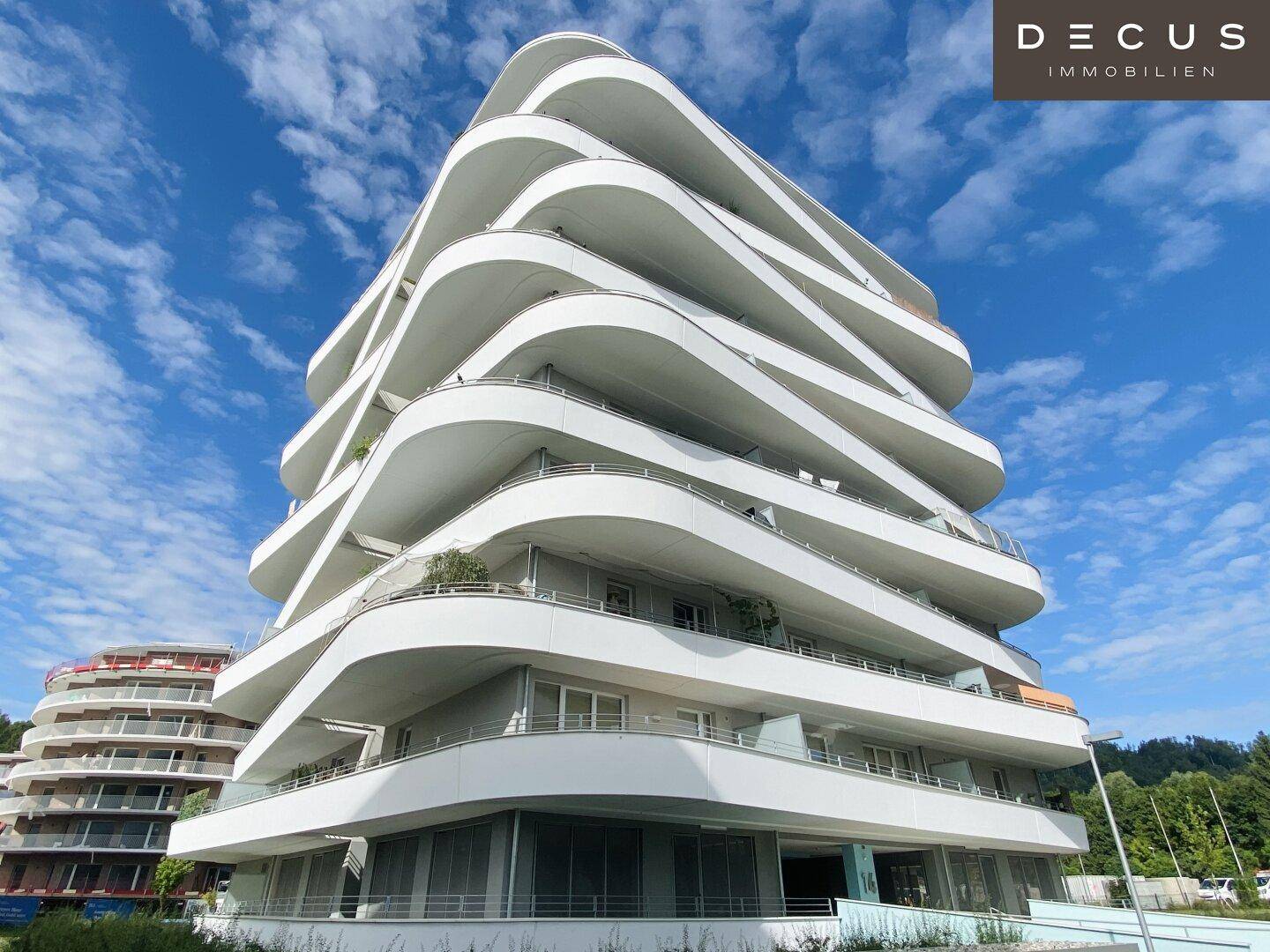 Moderne Architektur mit geschwungenen Balkonen unter blauem Himmel und viel Tageslicht.