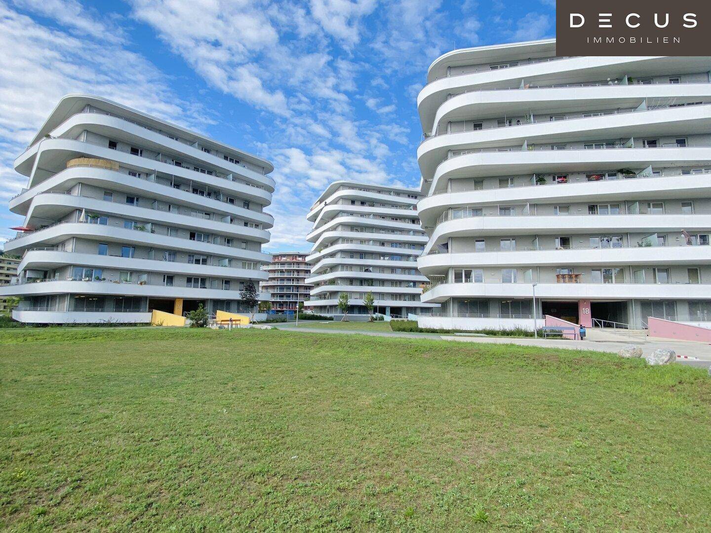 Weitläufige Grünflächen umgeben moderne Wohngebäude mit markanten, geschwungenen Balkonen.
