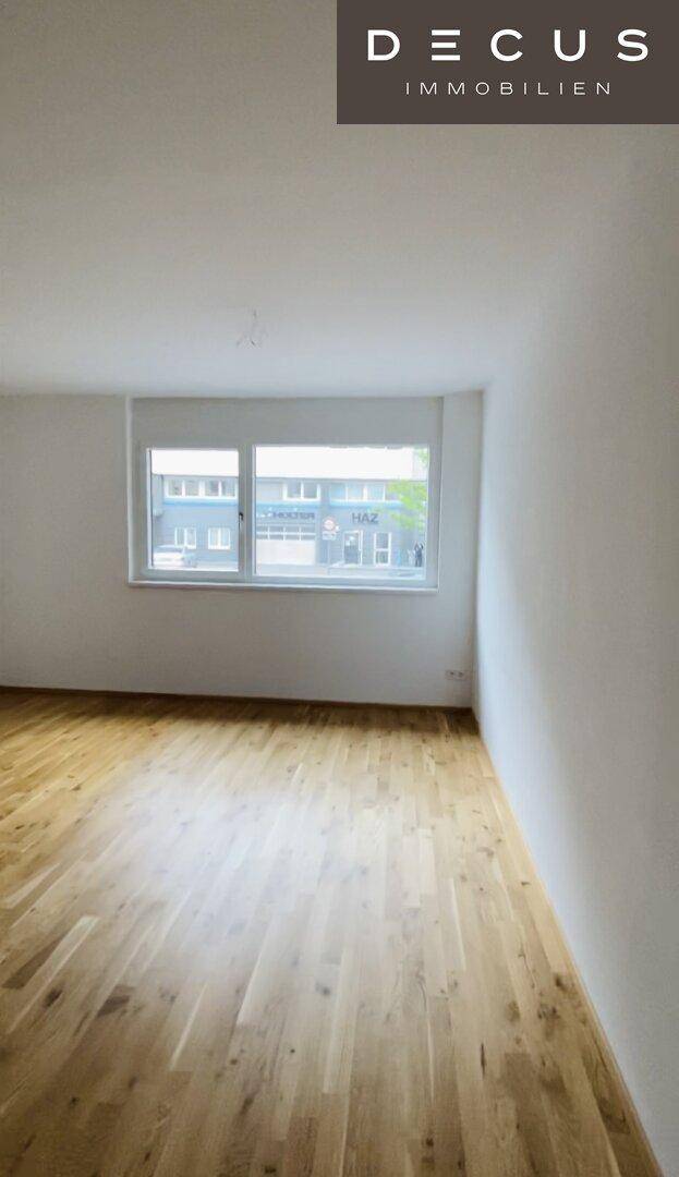 Heller Raum mit großem Fenster und Holzparkett, bereit zur individuellen Gestaltung.