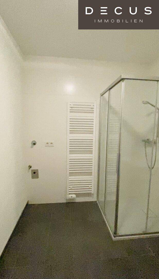 Modernes Badezimmer mit Duschkabine, beheiztem Handtuchhalter und dunklen Fliesen.