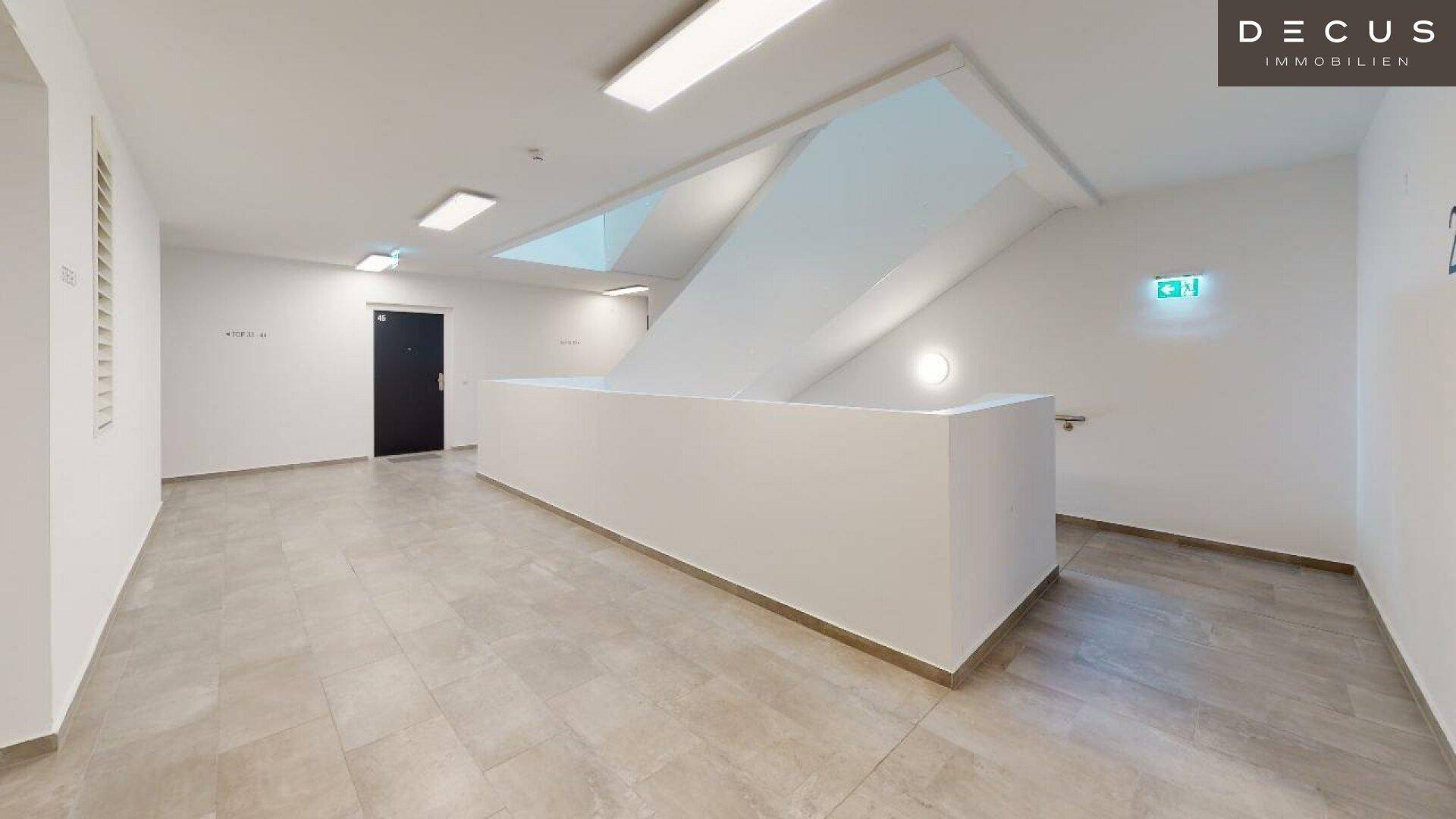 Geräumiger Flur mit modernem Treppenaufgang und heller Beleuchtung in einem Mehrfamilienhaus.