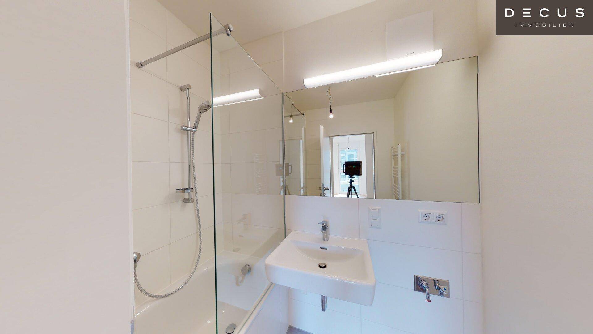 Modernes Badezimmer mit Badewanne, integrierter Dusche, Einzelwaschbecken und großem Spiegel.