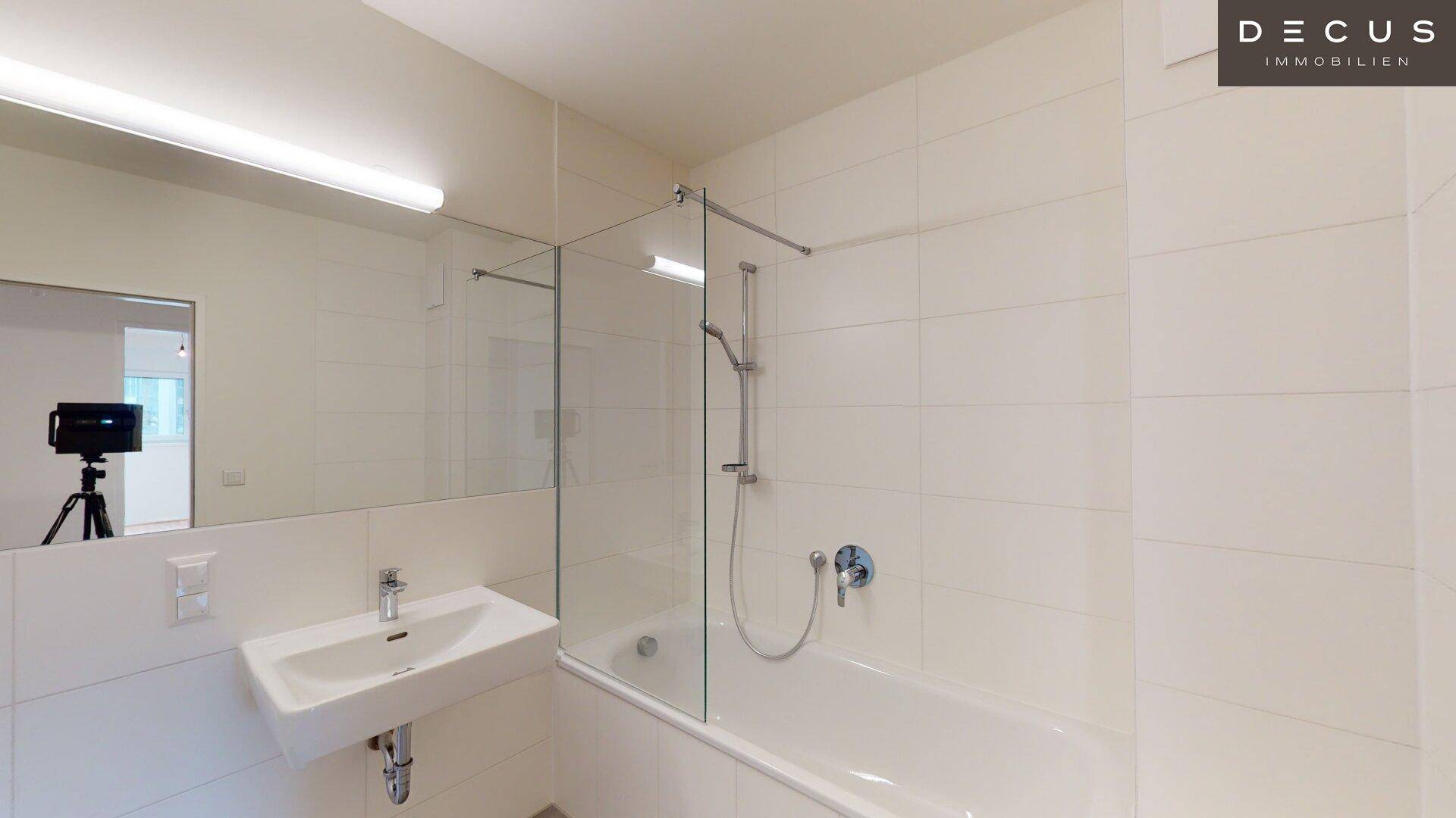 Modernes Badezimmer mit Badewanne, Dusche und weiß gefliesten Wänden, sehr gepflegt.