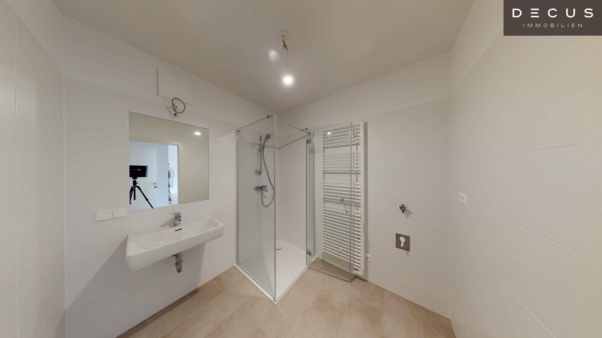 Helles Badezimmer mit moderner Eckdusche, Einzelwaschbecken und beheiztem Handtuchhalter.