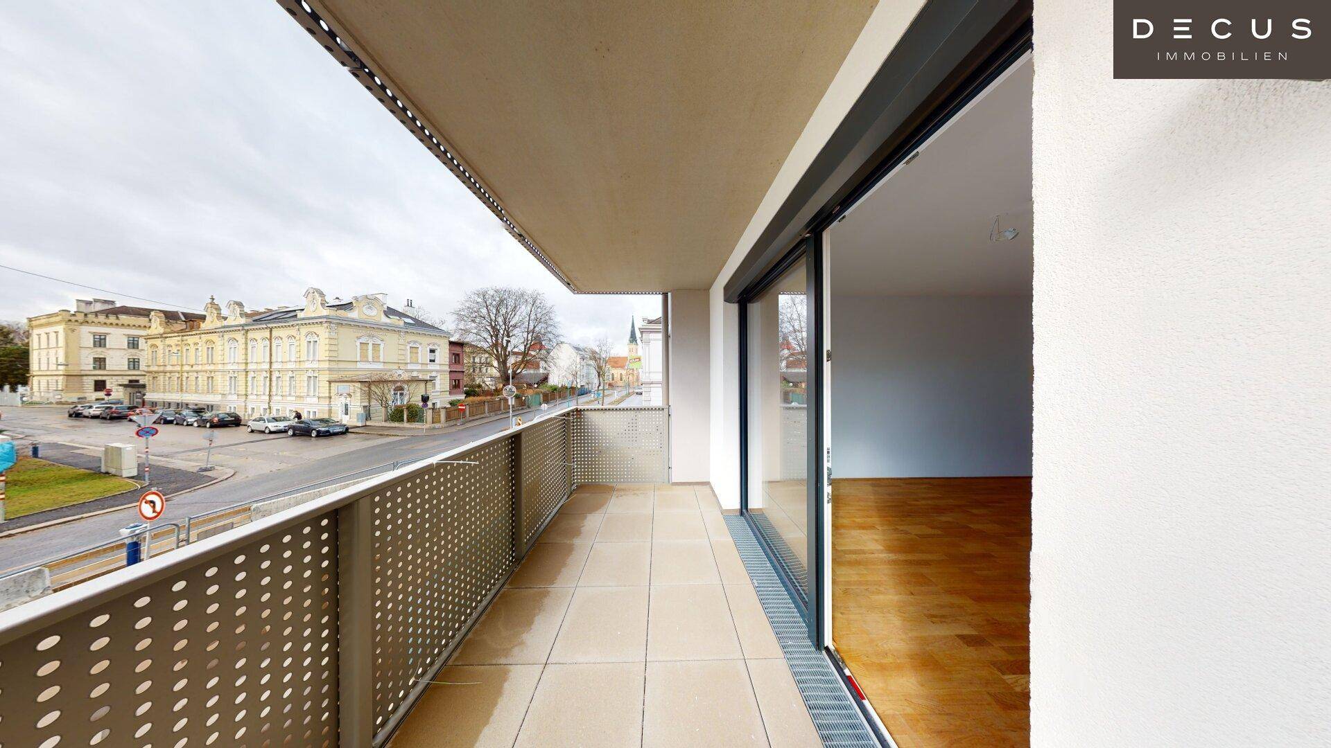 Heller Balkon mit Fliesenboden und Schiebetür zum Innenbereich, bietet Stadtblick.
