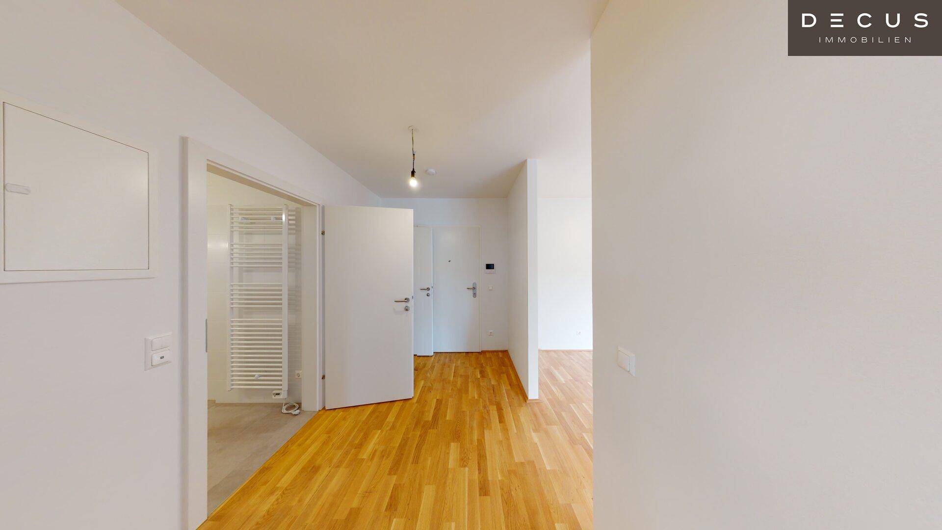 Heller Flur mit Parkettboden und Zugang zu verschiedenen Zimmern, inklusive Badezimmer.