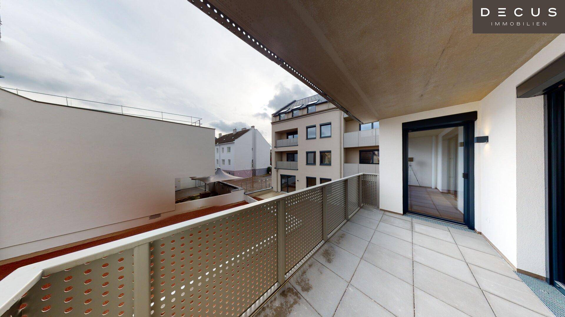 Balkon mit Fliesenboden und Blick auf die Nachbargebäude und den Innenhofbereich.