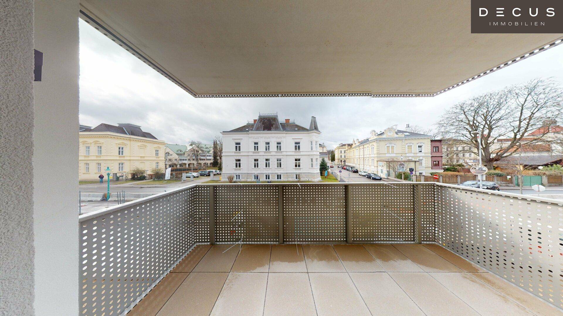 Großer Balkon mit Fliesenboden und weitem Blick auf die Stadt und umliegende Gebäude.