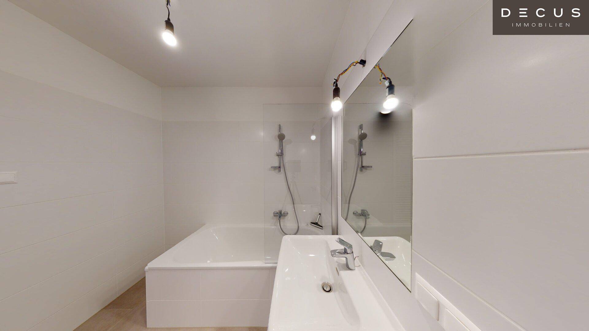 Modernes Badezimmer mit Badewanne, Duschvorrichtung und großem Spiegel über dem Waschbecken.