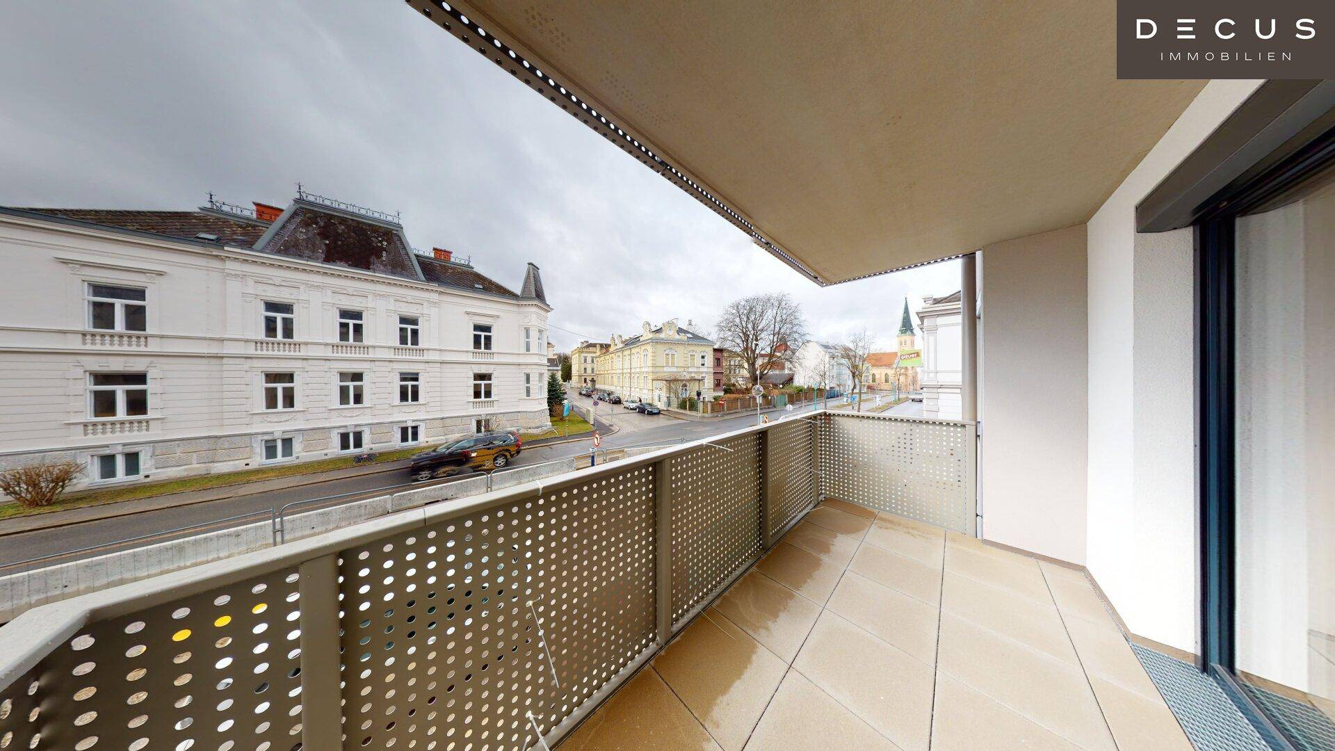 Balkon mit Fliesenboden und Blick auf die Straße und historische Gebäude.