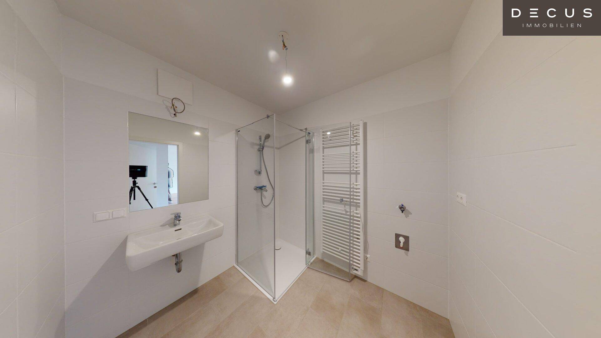 Modernes Badezimmer mit Duschkabine, Waschbecken und beheiztem Handtuchhalter.