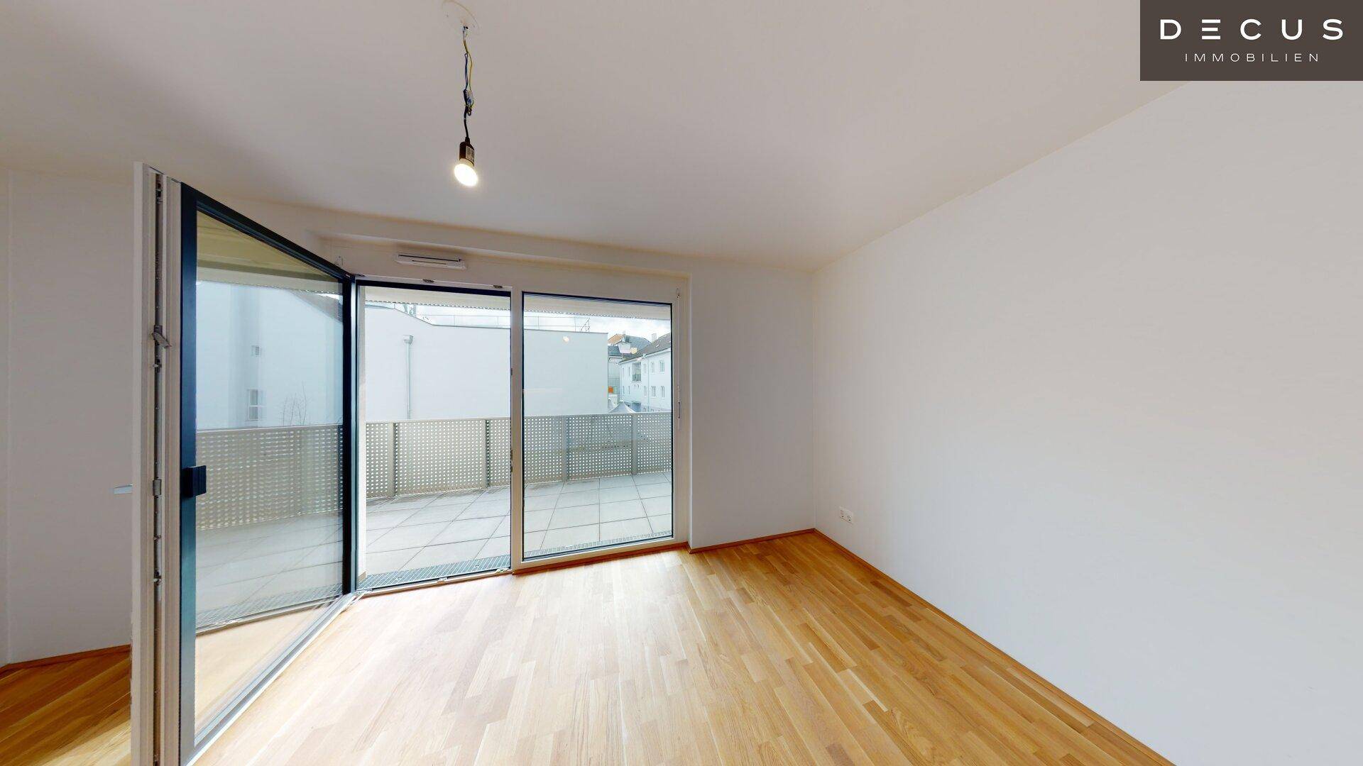Helles Schlafzimmer mit Parkettboden und direktem Zugang zum Balkon.