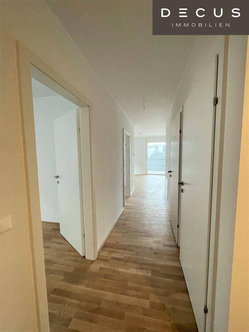 Langer, heller Flur mit Holzboden und mehreren Türen, der die verschiedenen Wohnbereiche verbindet.