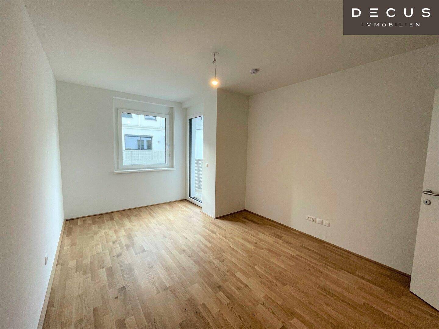 Helles Zimmer mit Parkettboden und großem Fenster, ideal als Schlaf- oder Arbeitszimmer nutzbar.