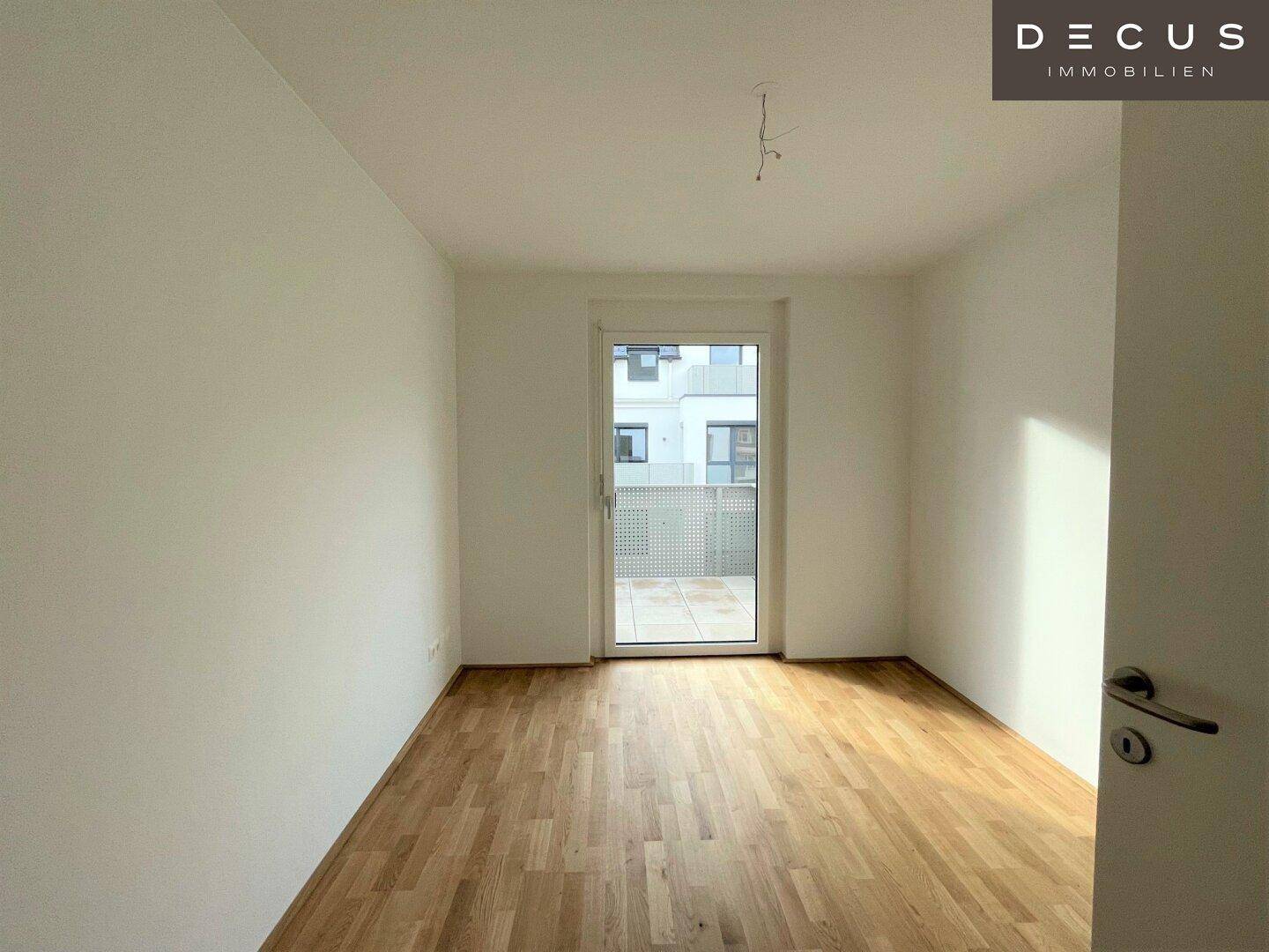 Helles Zimmer mit Parkettboden und Zugang zu einem Außenbereich, vielseitig nutzbar.