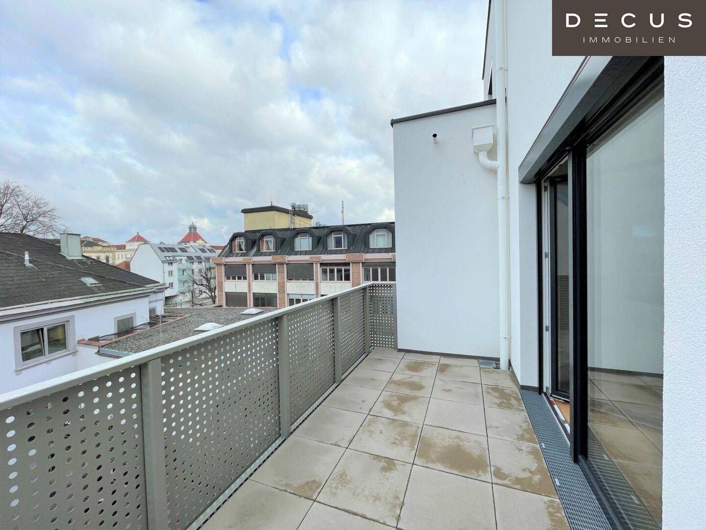 Geräumige Terrasse mit Fliesenboden und Blick auf die Stadt und umliegende Gebäude.