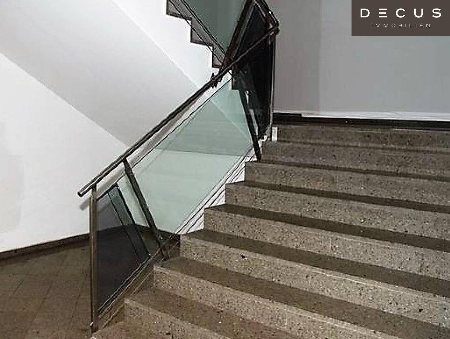 Modernes Treppenhaus mit Betontreppen und elegantem Geländer aus Glas und Metall.