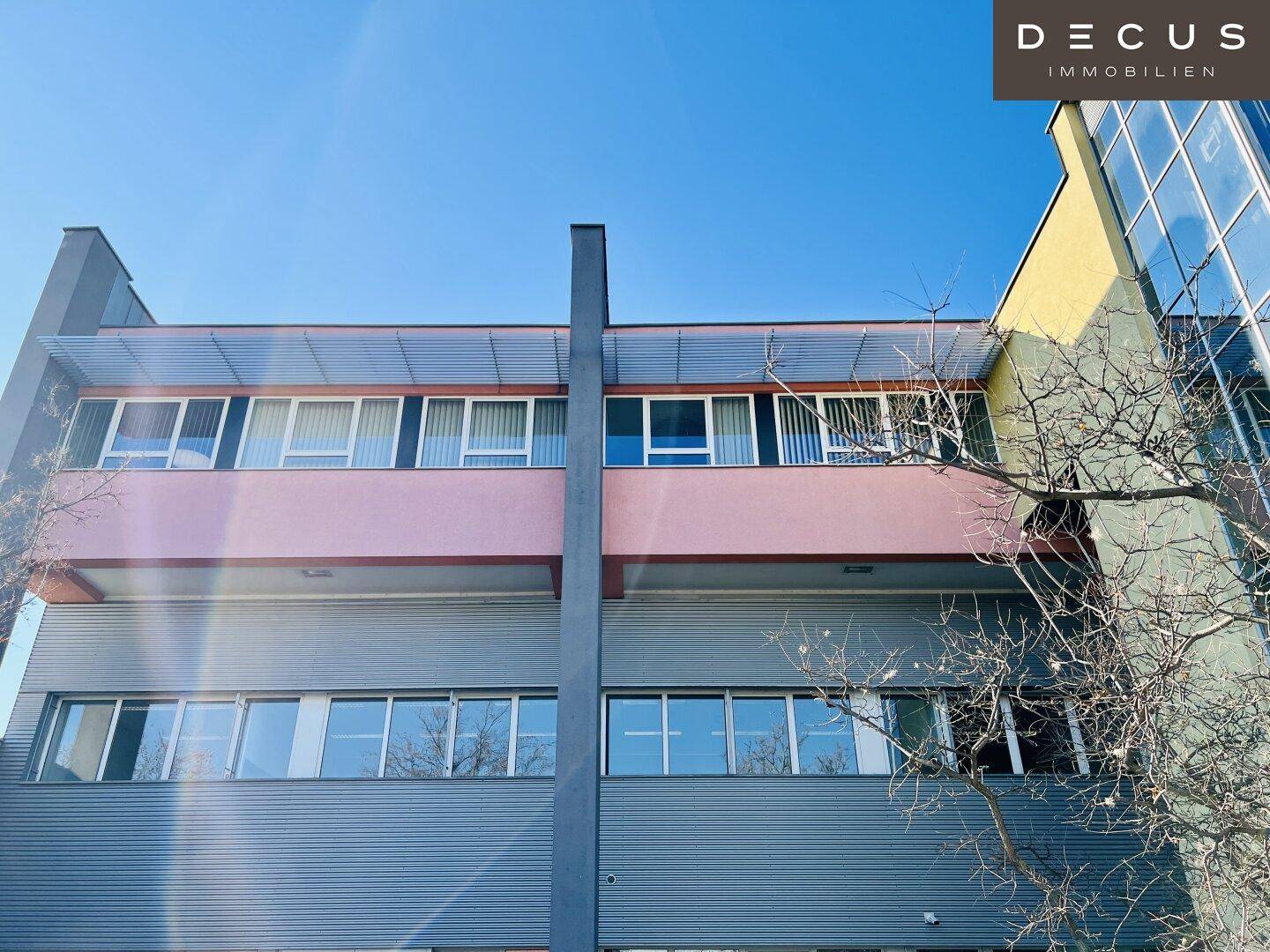 Fassade eines modernen Bürogebäudes mit verschiedenen Farben und großen Fenstern.