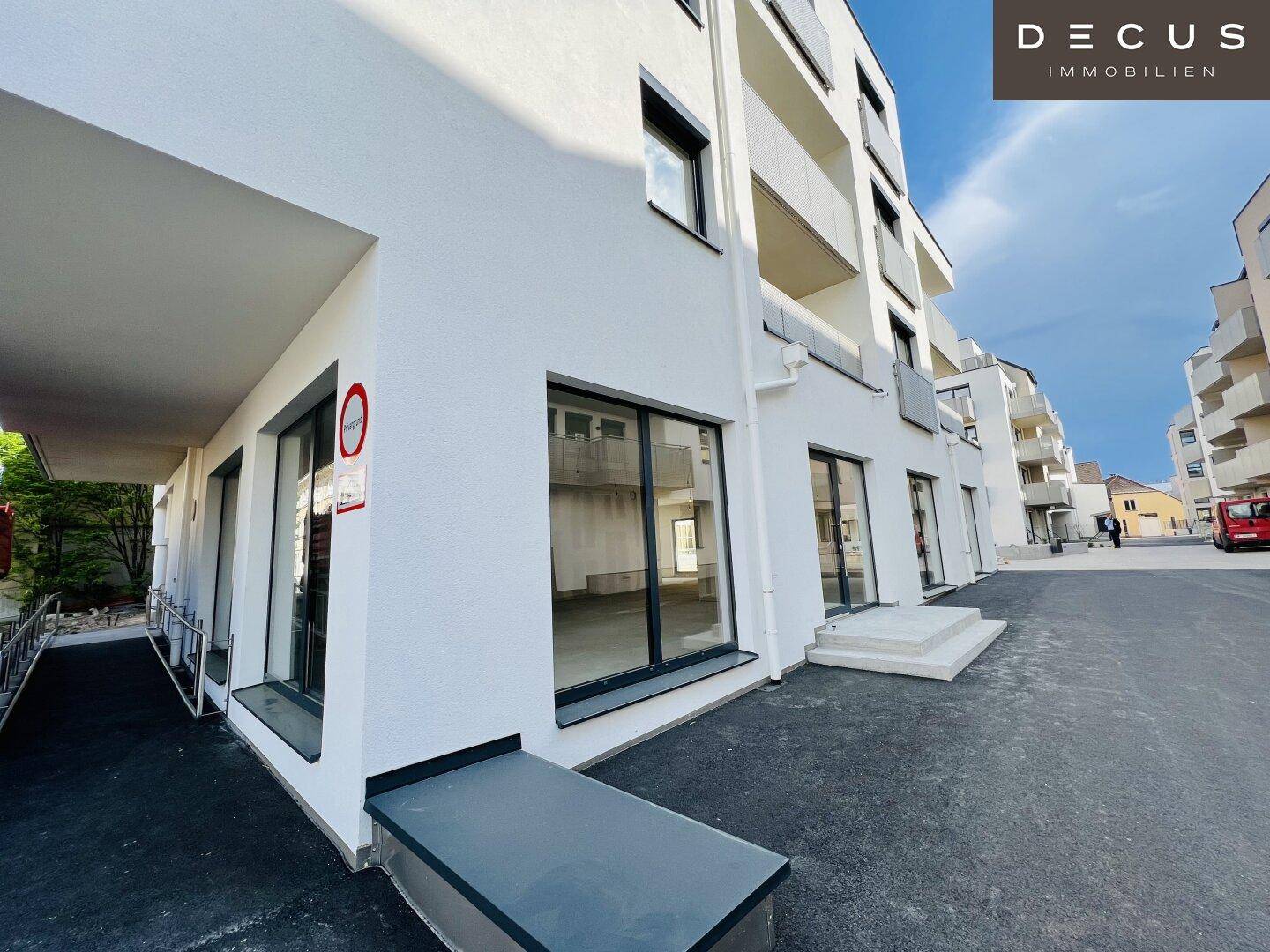 Moderne Gebäudefassade mit großen Fenstern und einer barrierefreien Rampe am Eingangsbereich.