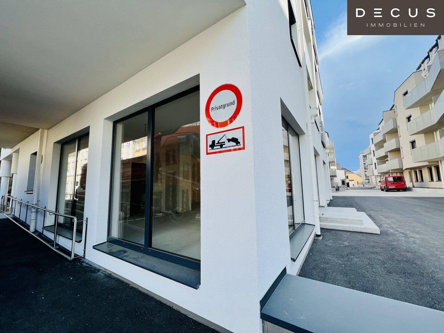 Gebäudeecke mit großen Fenstern und einem Hinweisschild auf Privatgrund, inklusive Zugangsrampe.
