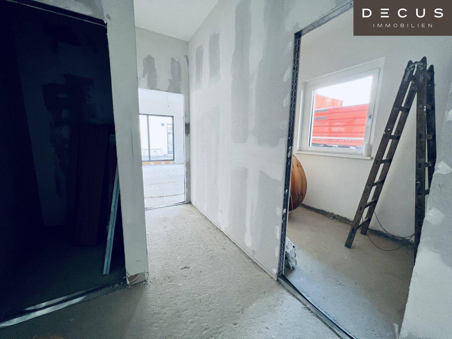 Kleiner Raum im Rohbau mit einem Fenster und einer Leiter, bereit für den weiteren Ausbau.