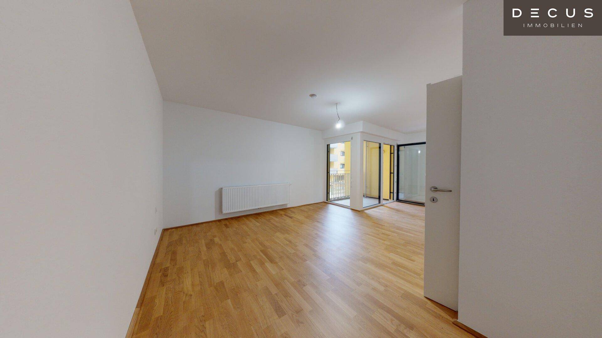 Geräumiges Wohnzimmer mit hellem Parkettboden und großzügigem Zugang zum Außenbereich.