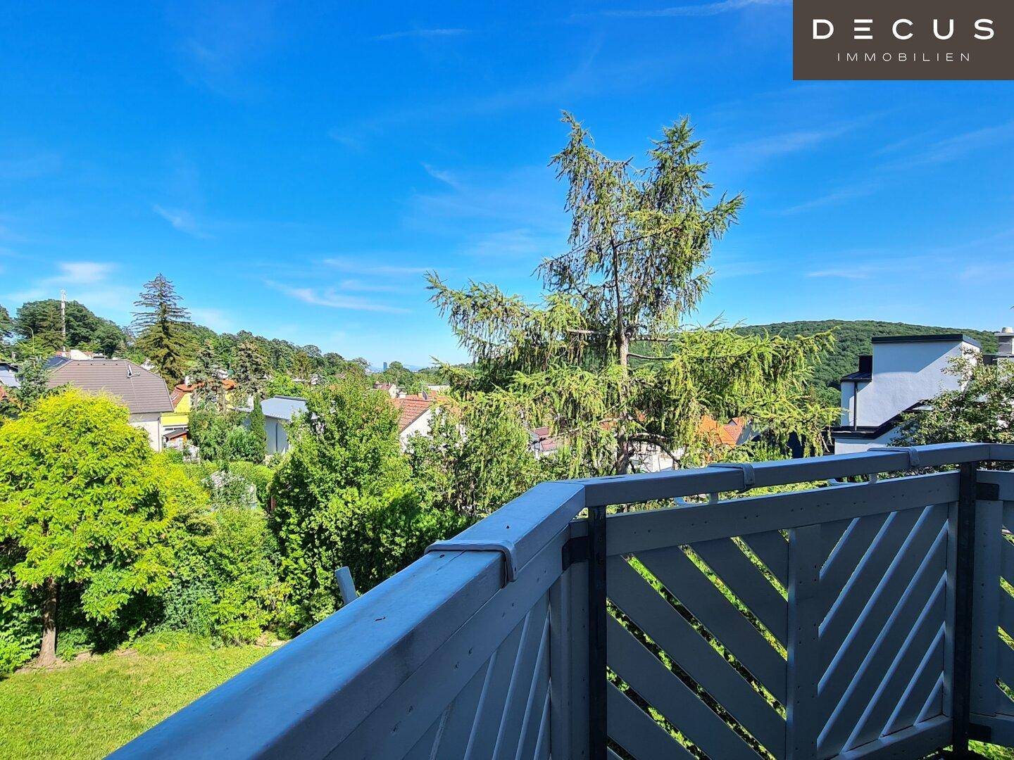Weitblick vom Balkon über grüne Baumwipfel und die umliegende Wohngegend.