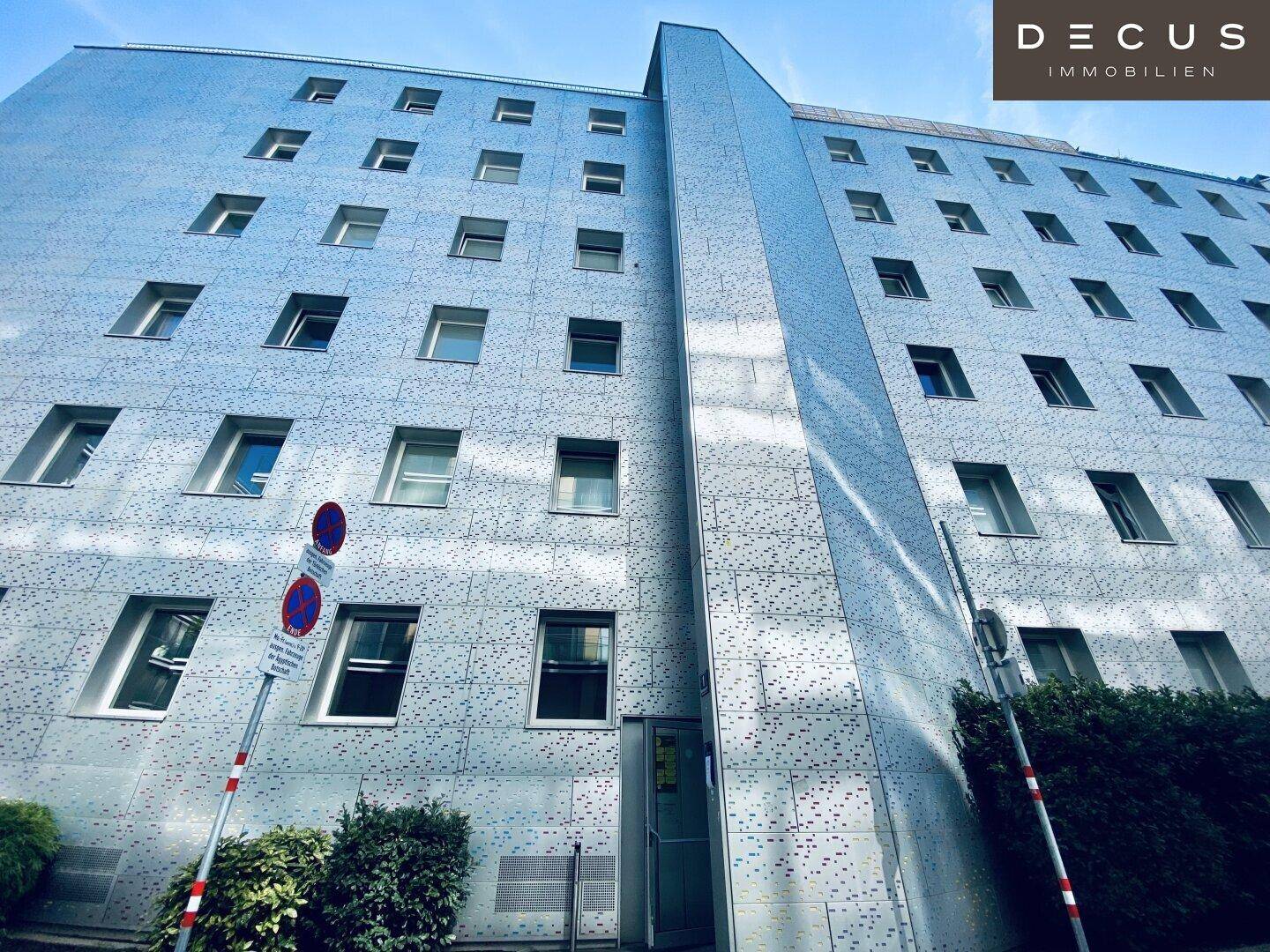 Moderne Gebäudefassade mit vielen Fenstern und einer strukturierten Oberfläche unter blauem Himmel.