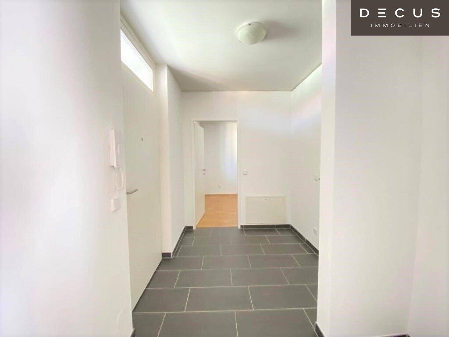 Heller Flur mit modernen grauen Fliesen und Gegensprechanlage.