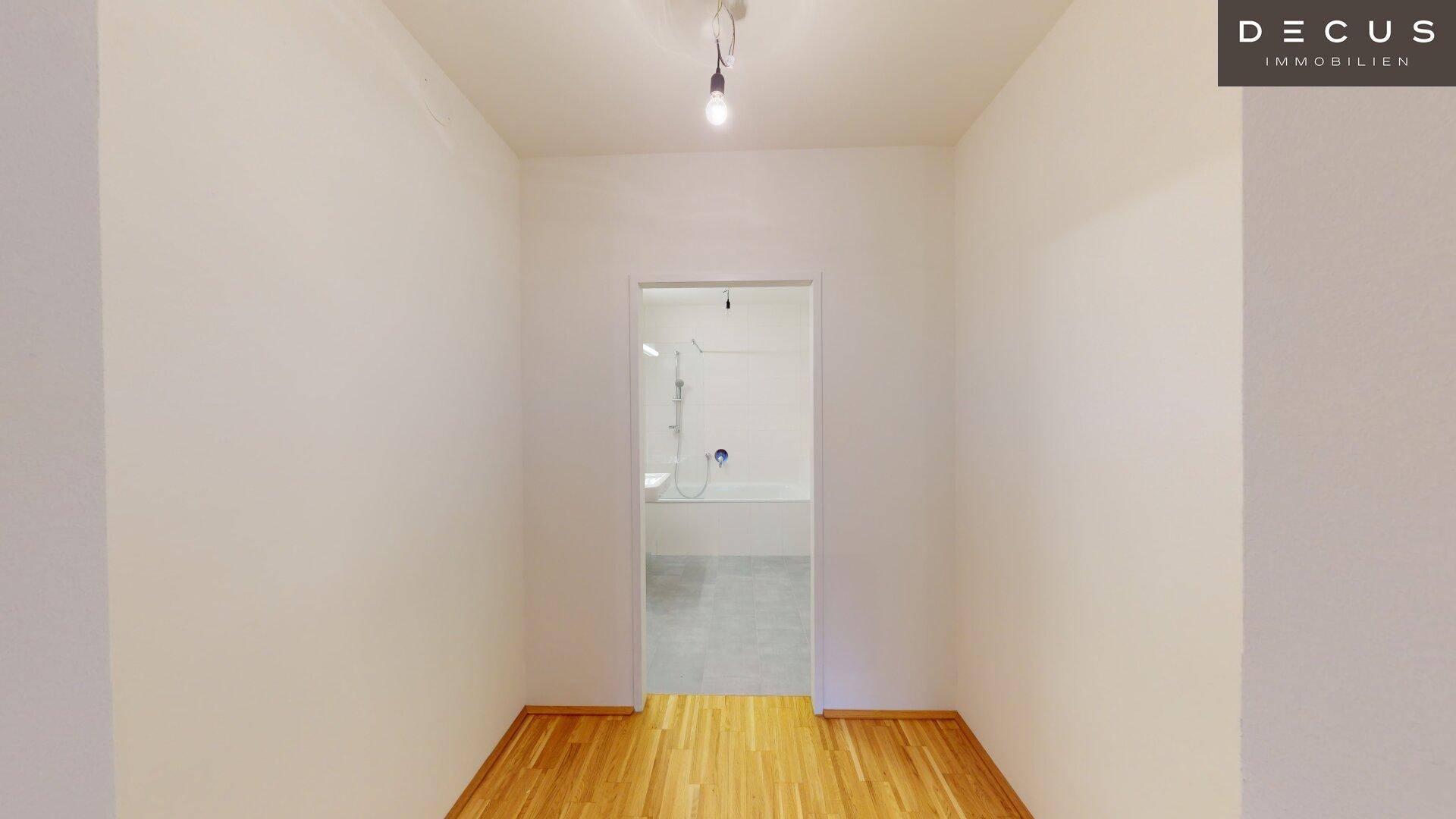 Leeres Zimmer mit Parkettboden und direktem Zugang zu einem modernen Badezimmer.