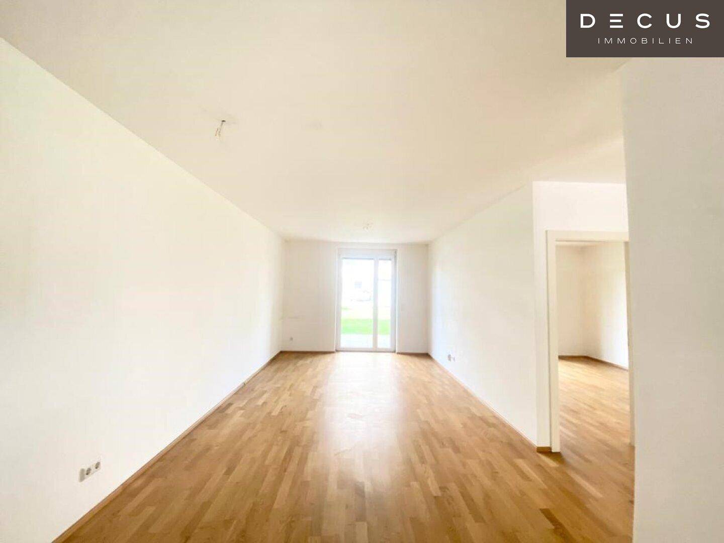 Geräumiges, helles Wohnzimmer mit Parkettboden und Zugang zum Balkon.
