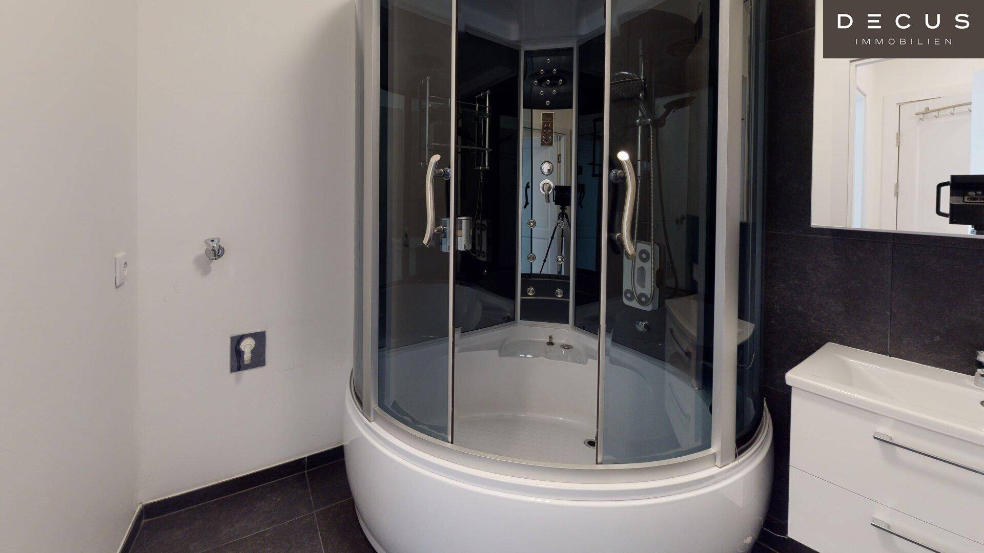 Modernes Badezimmer mit dunklen Fliesen, Duschkabine und Waschtischunterschrank.