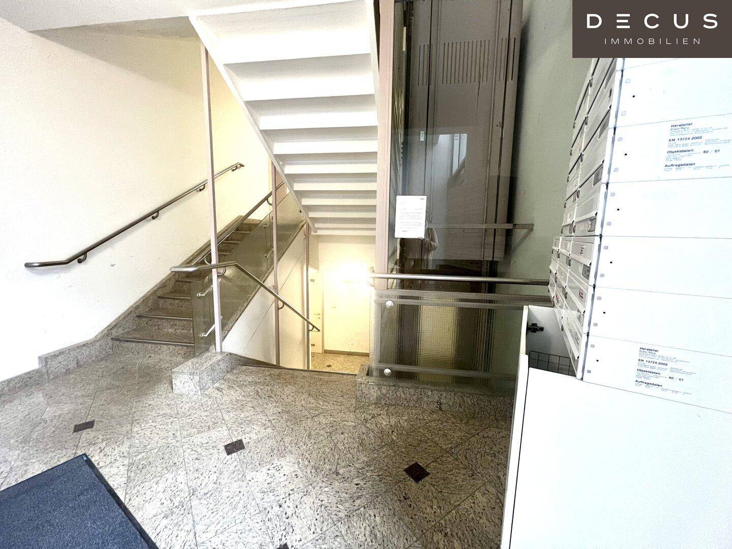 Treppenhaus mit Granitboden und modernem Aufzug, bietet Zugang zu den oberen Etagen.