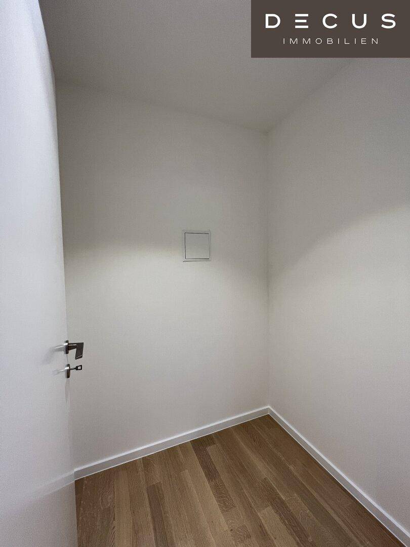 Kleiner, leerer Abstellraum mit Holzboden und weißen Wänden, ideal für zusätzlichen Stauraum.