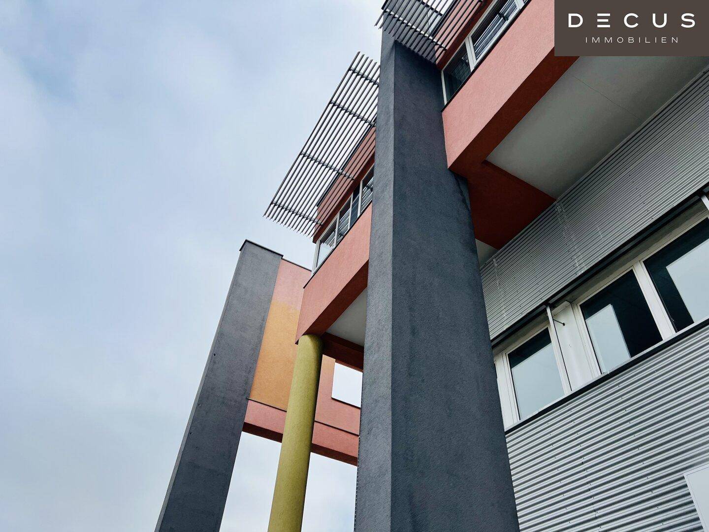 Moderne Gebäudefassade mit farbigen Akzenten, großen Fenstern und architektonischen Säulen.