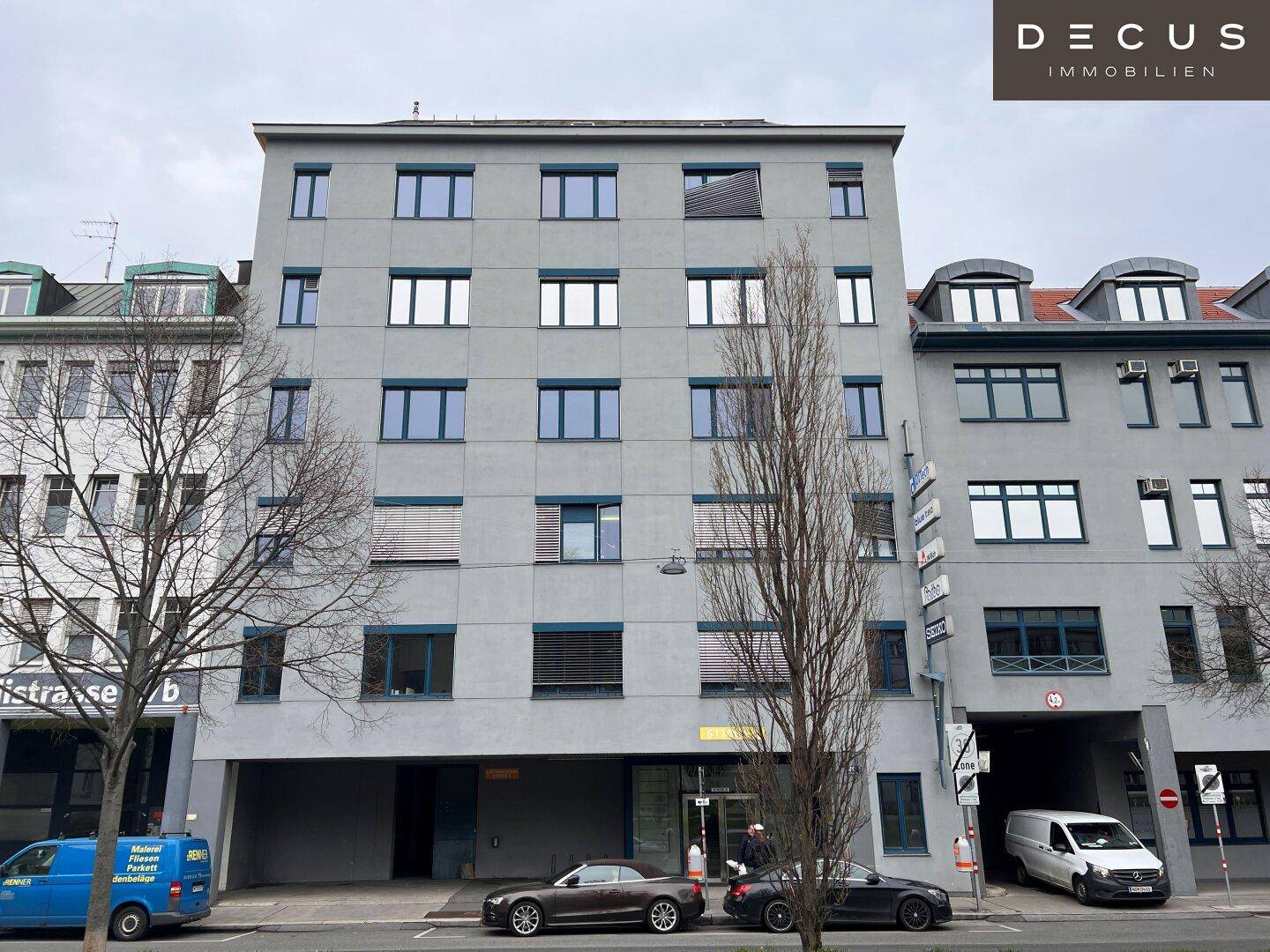 Moderne Fassade eines Bürogebäudes mit vielen Fenstern und Jalousien an einem bewölkten Tag.