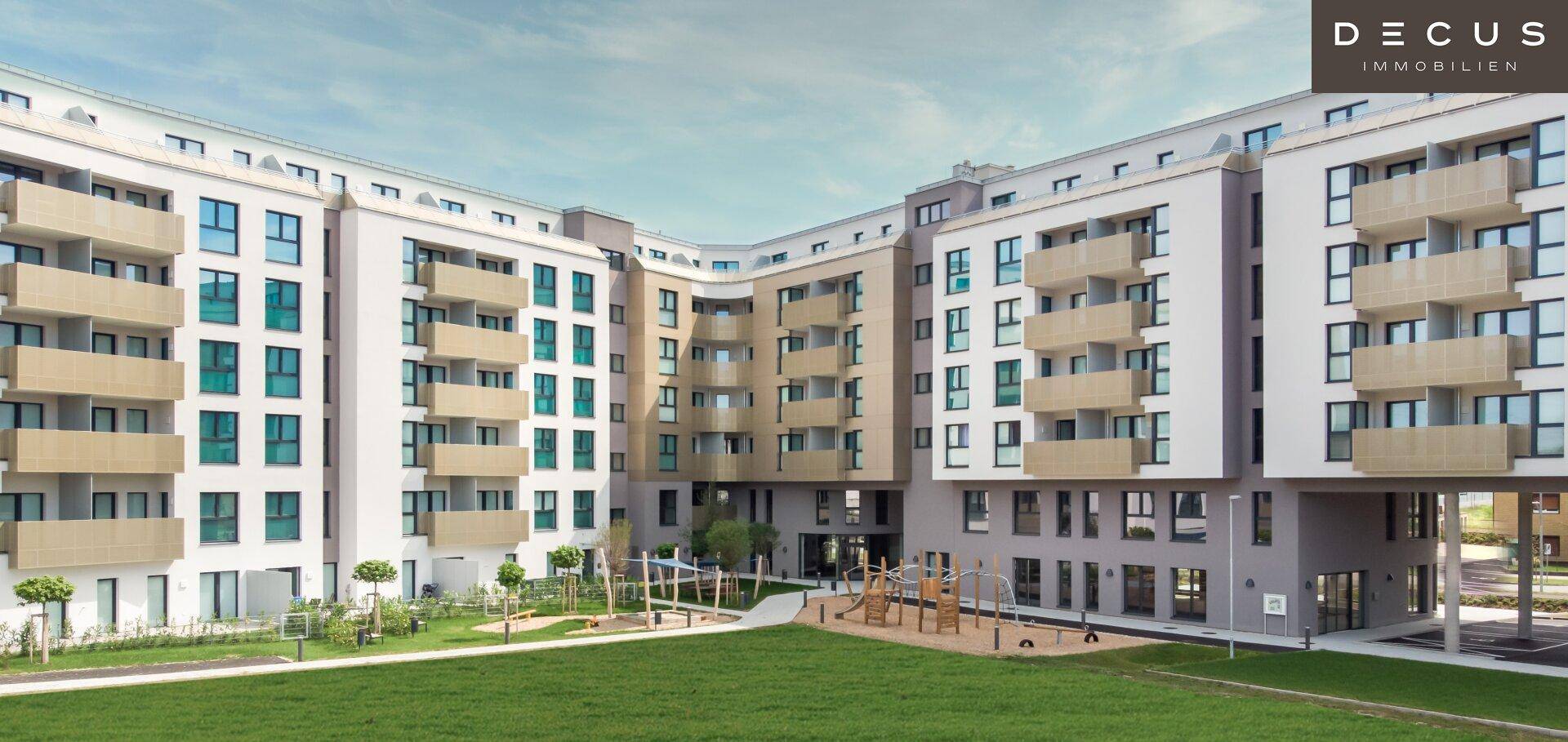 Weitläufige Ansicht des modernen Apartmentkomplexes mit geschwungener Architektur und zentralem Spielplatz.