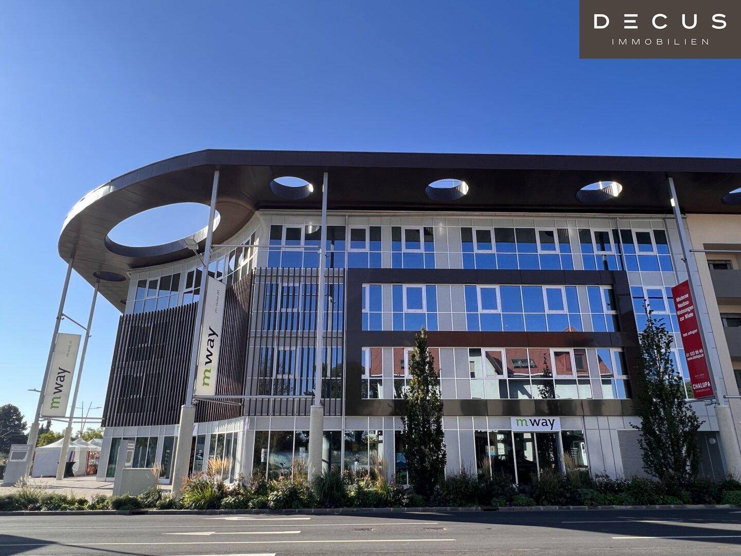 Seitenansicht des modernen Bürogebäudes mit reflektierenden Fenstern und klarem Himmel.