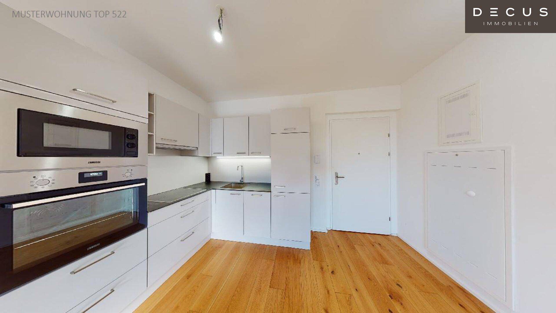 Moderne Einbauküche mit weißen Fronten, integrierten Geräten und Holzboden.