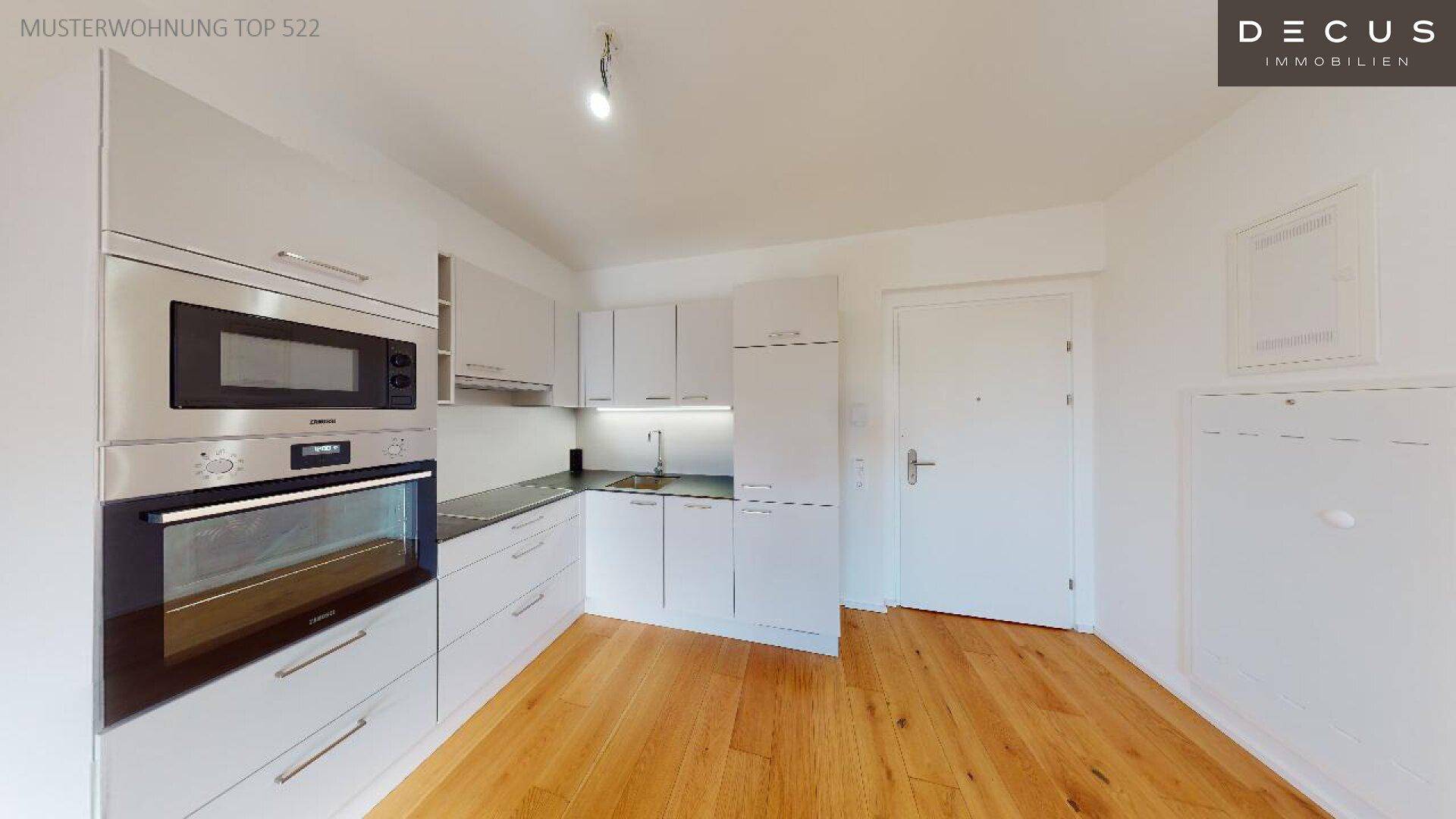 Funktionale Küche mit weißen Schränken, Backofen und Mikrowelle, auf Holzboden.
