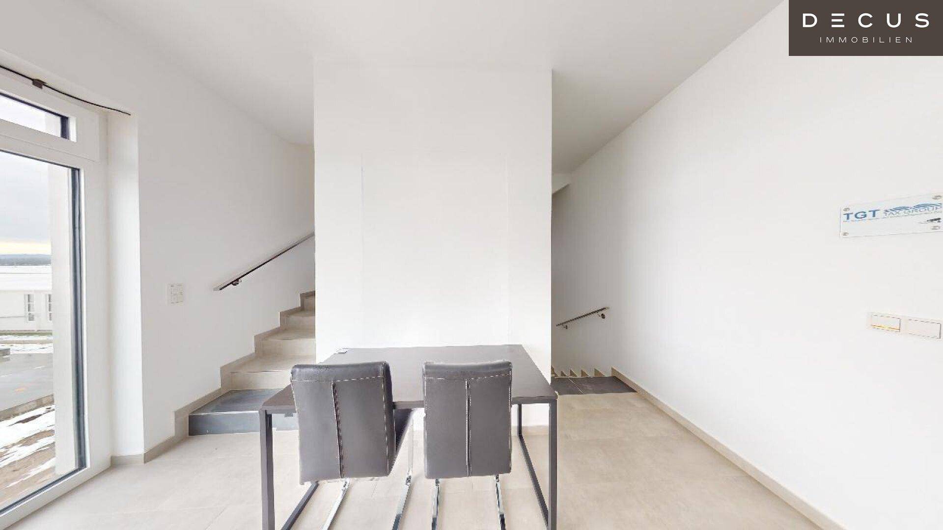 Eingangsbereich mit kleinem Tisch, Stühlen und Zugang nach draußen, daneben eine Treppe.