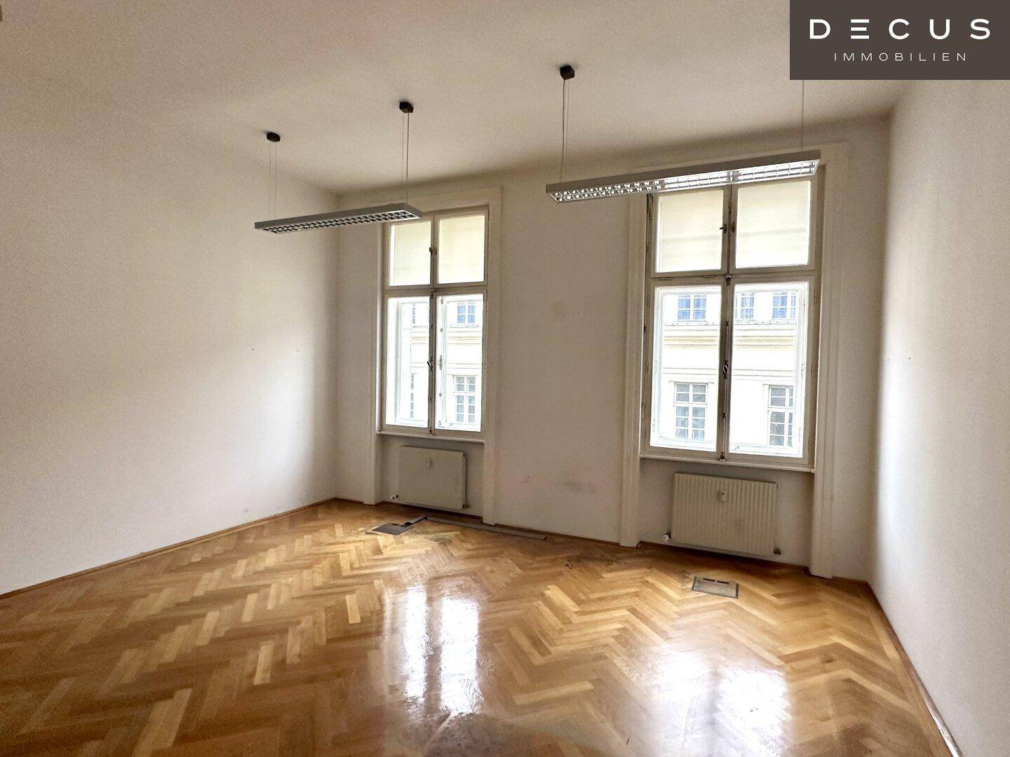 Helles Büro mit Fischgrätparkett und zwei großen Fenstern, bietet eine angenehme Arbeitsatmosphäre.