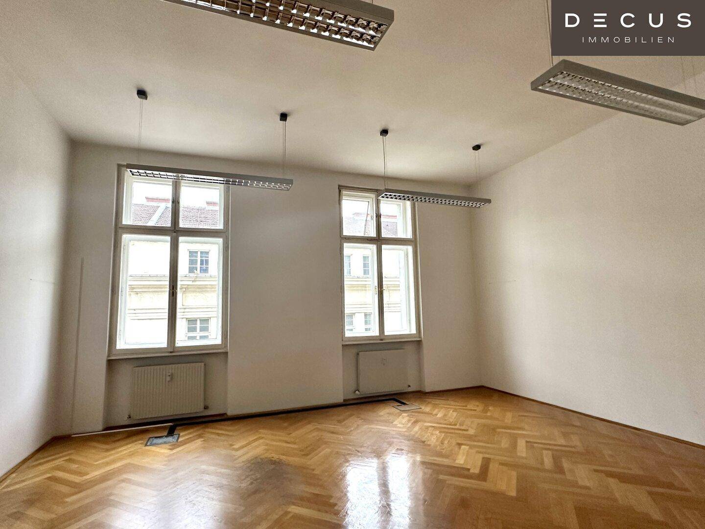 Geräumiges Büro mit Fischgrätparkett und hohen Fenstern, ideal für konzentriertes Arbeiten.