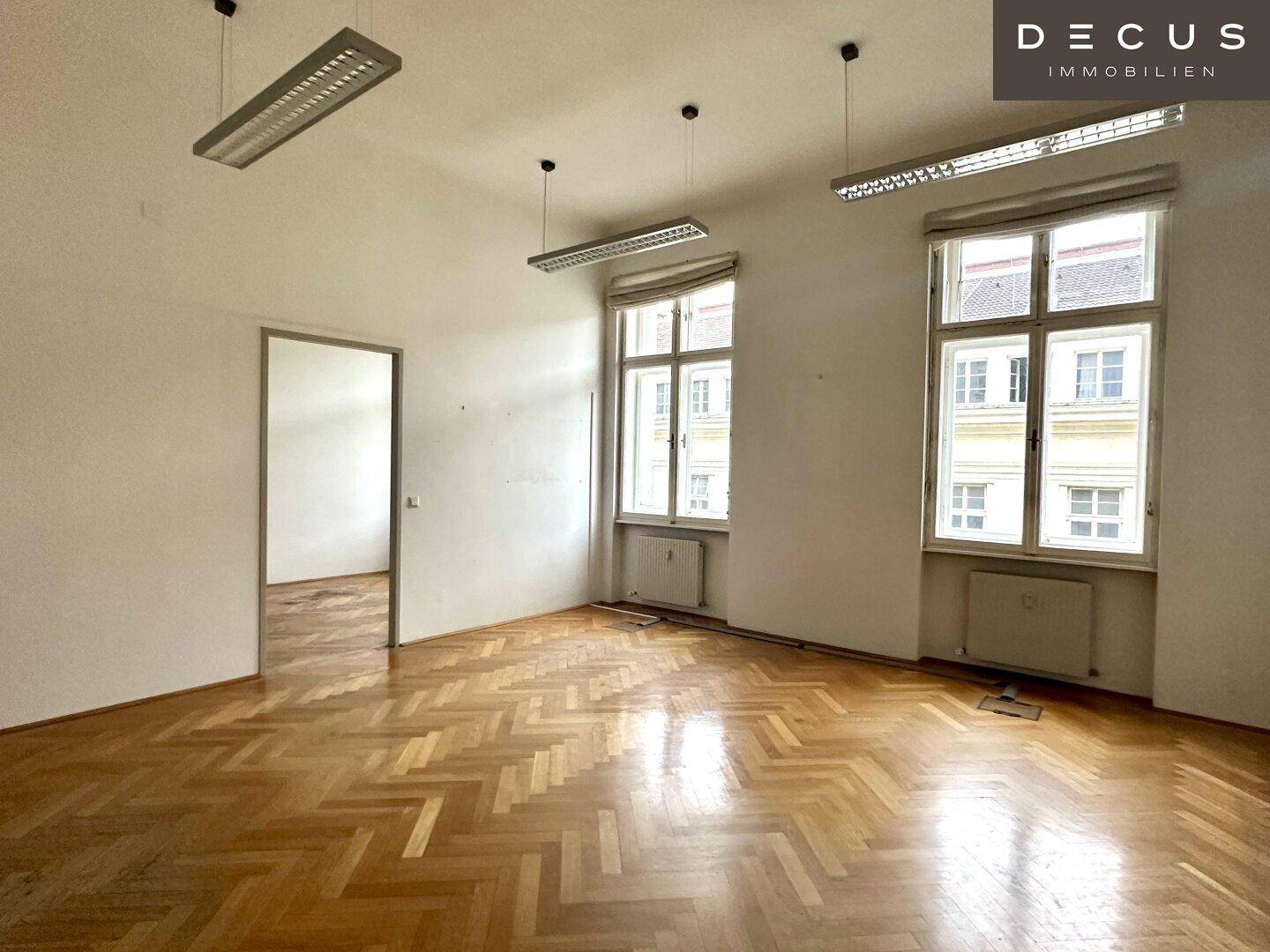 Heller Büroraum mit Fischgrätparkett und Zugang zu einem weiteren Zimmer, bietet Flexibilität.