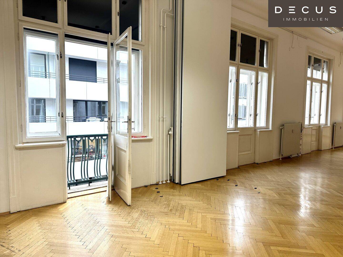 Heller Raum mit Fischgrätparkett und Zugang zu einem kleinen Balkon, bietet viel Tageslicht.
