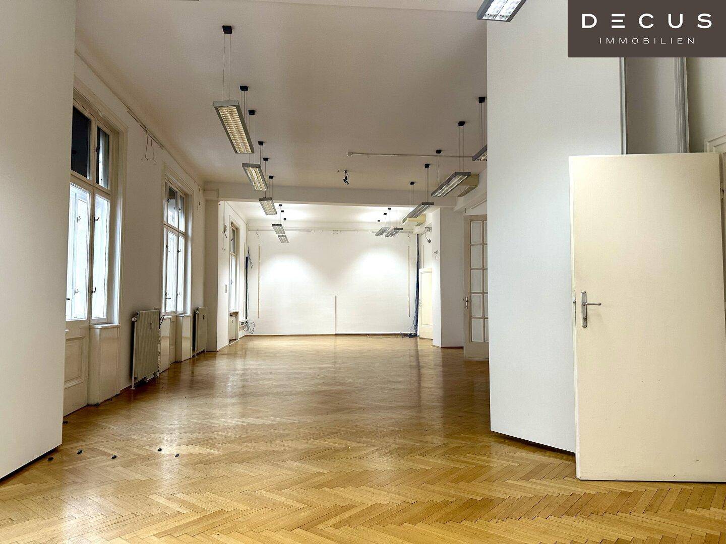 Großer, heller Büroraum mit Fischgrätparkett und hohen Fenstern, bereit zur individuellen Gestaltung.